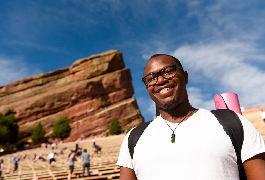 An African American man with his yoga mat slung over his shoulder at Red Rocks Amphitheater.