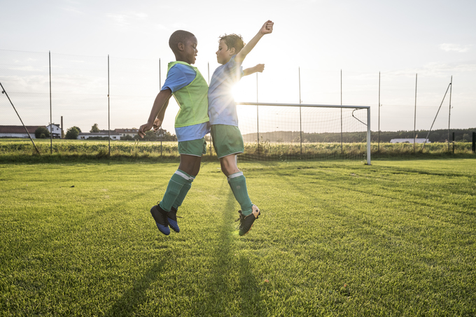 Young children celebrate on the soccer field with a chest bump in this photo.