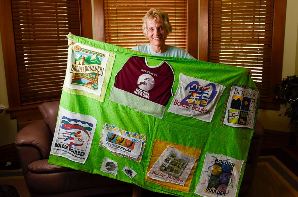 Runner Susa High poses with a quilt a friend made her. It features Boulder Bolder tee-shirts from the 41 races she's completed.