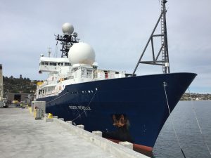big ship at a doc, with a large white ball on it that is radar.