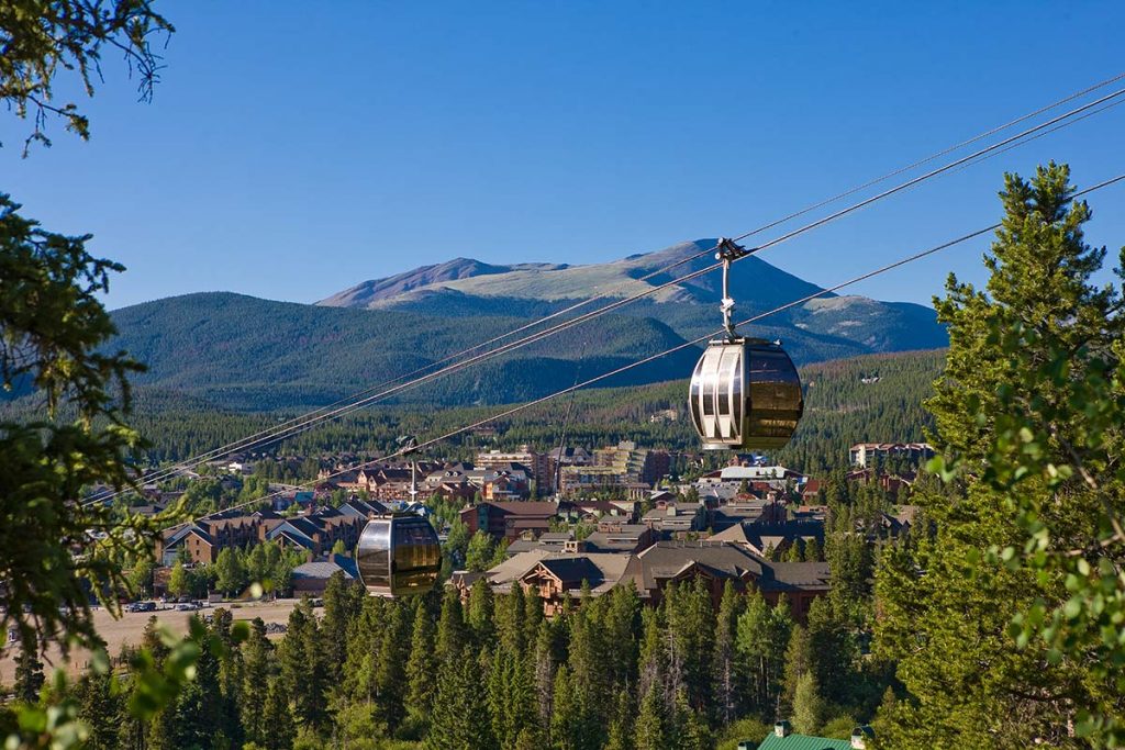 One of the free gondolas in Colorado is the BreckConnect gondoal in Breckenridge. Here you see a gondola car above the slopes with a mountain in the background.