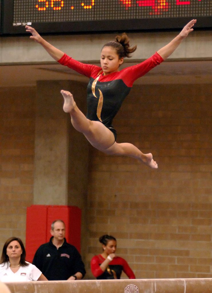 Olympic gymnas, Jessic López, does the splits on the balance beam while competing for the University of Denver.