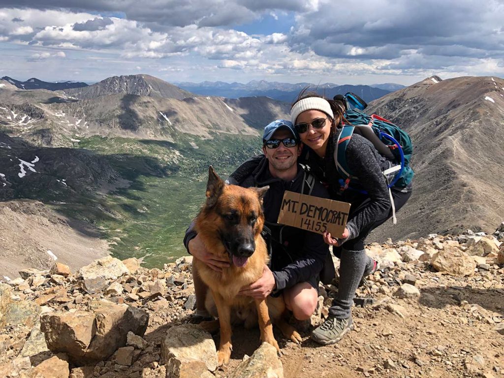 Olympic gymnast Jessica López at the top of a 14er with her boyfriend and her dog.