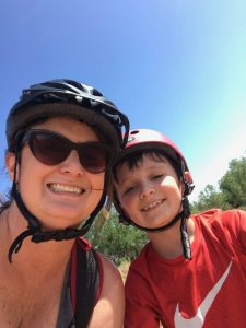 selfie of Kim and son with bike helmets on.