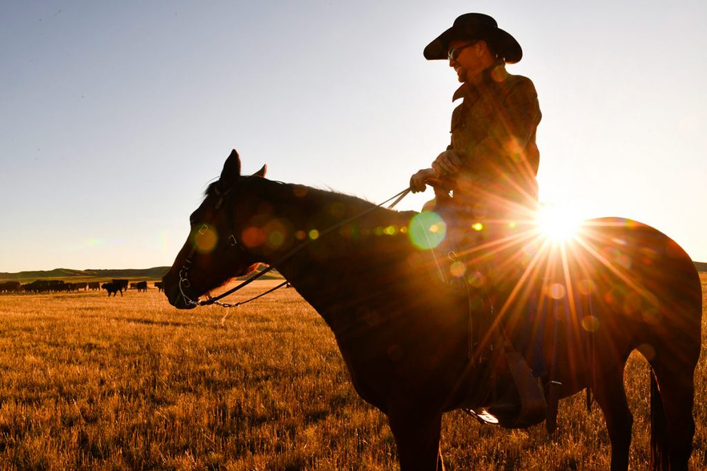 Nathan Kissack rides his horse Dixie on his parents' ranch in Wyoming as the sun sets behind him.