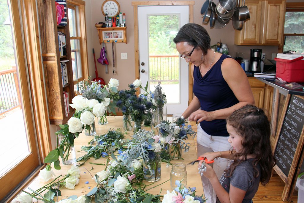 Alex and Jade Mathisen arrange flowers into glass vases at their kitchen table.