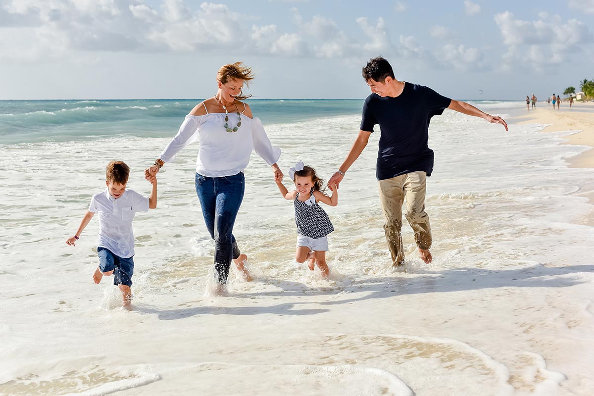 Parents running and holding hands with two kids at the beach, after David Procedure helped dad's heart.