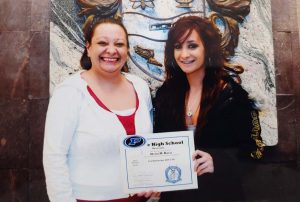 mother stands beside her daughter at high school graduation. mom credits her daughters great start to a prenatal care program.