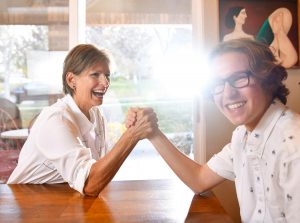 grandma and grandson arm wrestle at the kitchen table. Betty nas her strength back after having the first successful hepatitis C-infected liver transplant at UCH.
