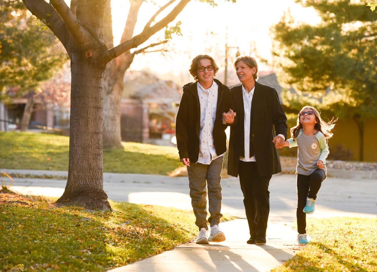 women walks down sidewalk while holding grandkid's hands after she had a hepatitis C-infected liver transplant.