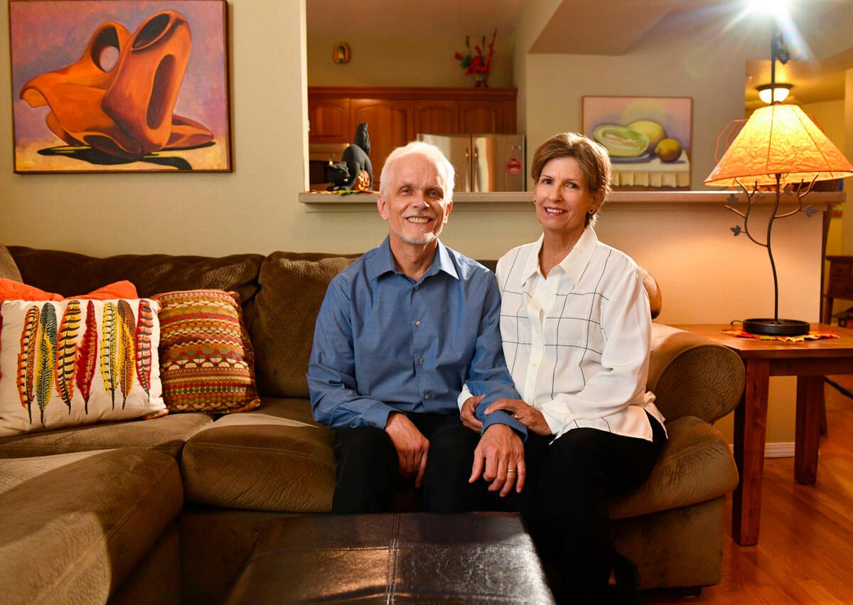 husband and wife sit together in their home.