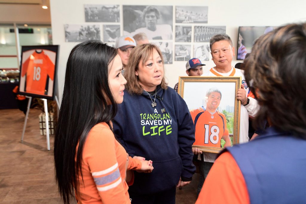 Linda Regis wears a sweatshirt saying, "A transplant saved my life" while she, a transplant recipient, meets family of the donor.