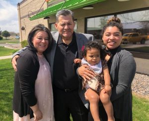 family stands in front of building for photograph.