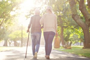 two women walk, one with a cane. fall prevention classes can help teach older people how to be safe.