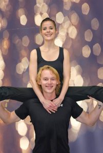 dancer with legs out on the shoulders of another dancer.