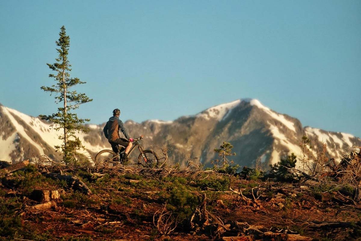 mountain biker resting on his bike looking at the large mountain range in the background after doctors repaired a devastating knee injury.