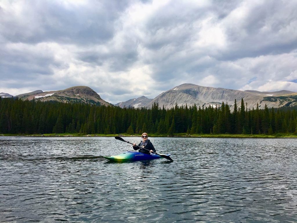 Lauren paddles a kayak on a mountain lake.