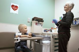 Boy sits next to his phlebotomist after she takes his blood at the hospital.