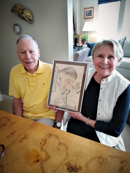 Wife holds a sketch of her husband when he was 21 while he, who is living with dementia and now 80, sits beside her.