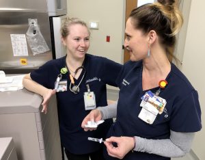 A nurse manager and a nurse discuss the hepatitis A vaccine