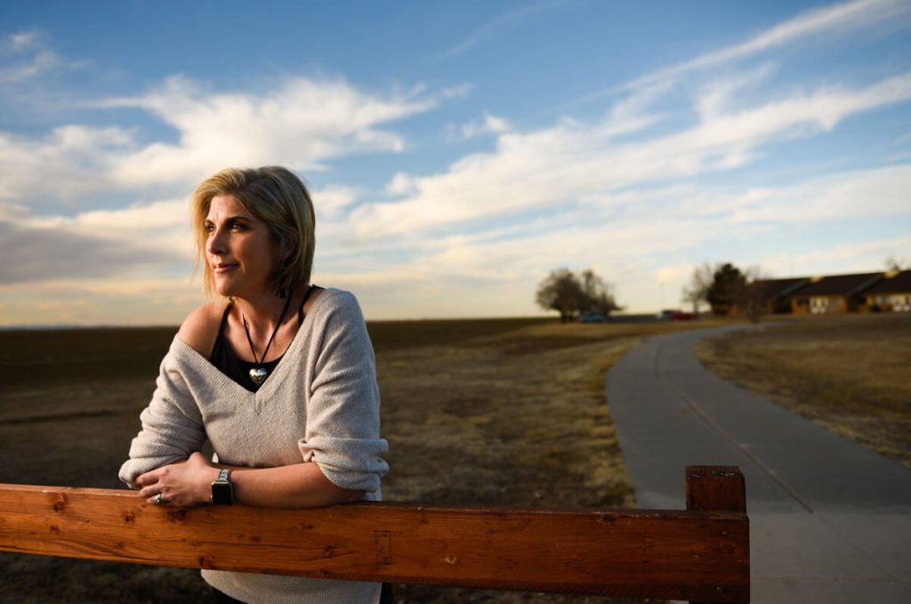 woman stands in front of fence showing off her weight loss through a weight management program in primary care
