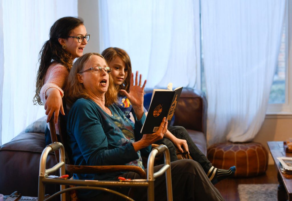 Fran Berger reading a book to grand kids with her walking nearby.
