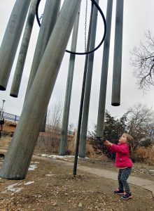 girl reaches up to play with massive chimes at the Swetsville Zoo, a free thing to do in northern Colorado.