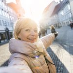 older adult takes a selfie while traveling, which isn't advised during the coronavirus outbreak.