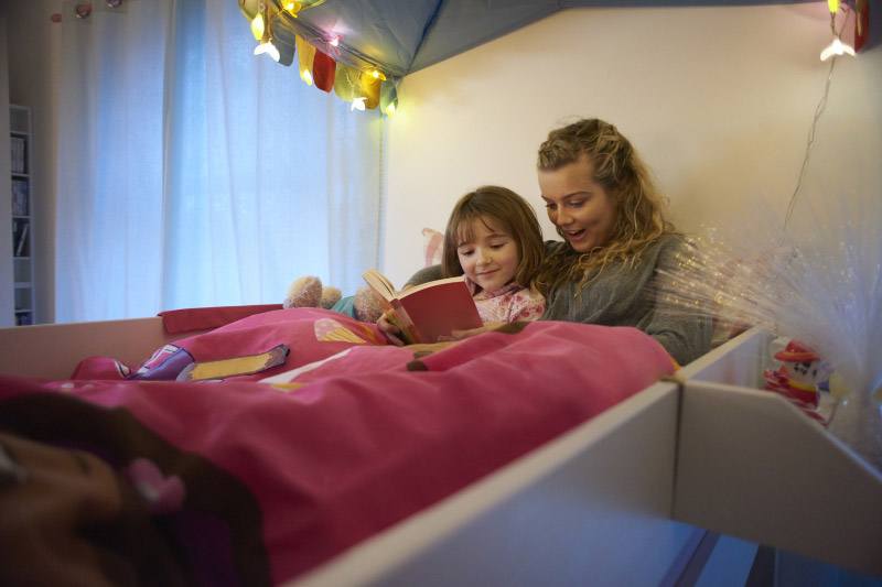 woman reading to a child in bed, one way in talking to children about coronavirus.