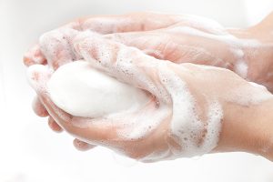 a person lathering up with soap shows why soap works better than hand sanitizer to remove the coronavirus