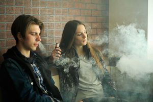 a young man and a woman vaping, and the coronavirus makes this more risky.