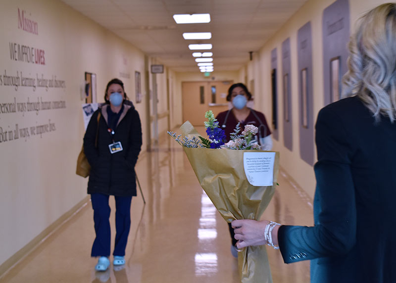 two health care workers walk down a hospital hallways towards a boutique of flowers donated as thanks.