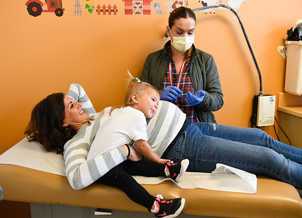 birth during pandemic - here big sister Harper Kronebusch lays her head on her mom's belly during a checkup