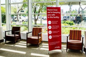 signs in a lobby explaining hospital safety during covid.