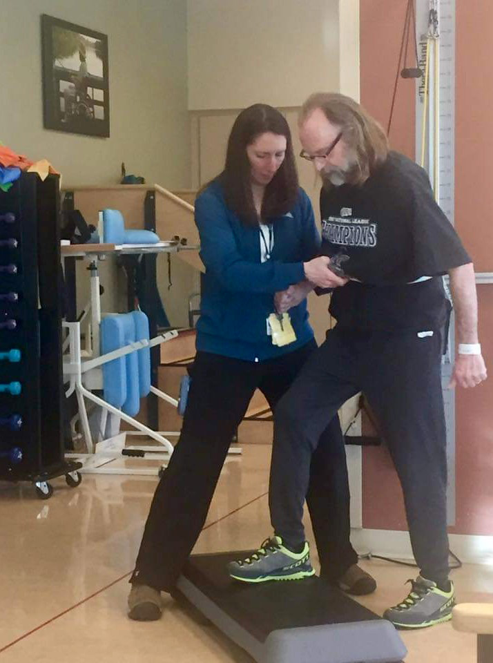 therapist at UCHealth hospital helping Jeff step up as part of his hemorrhagic stroke treatment.