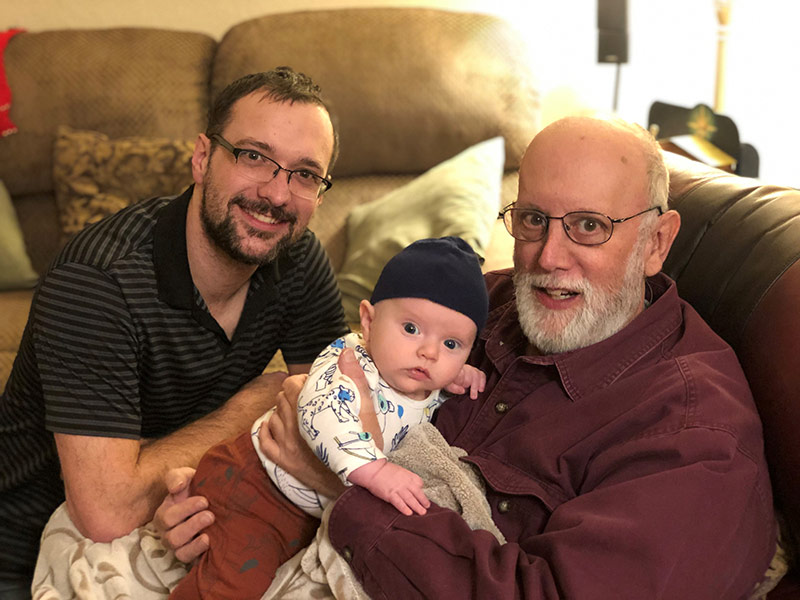 Jim holding his newest grandchild and his son.