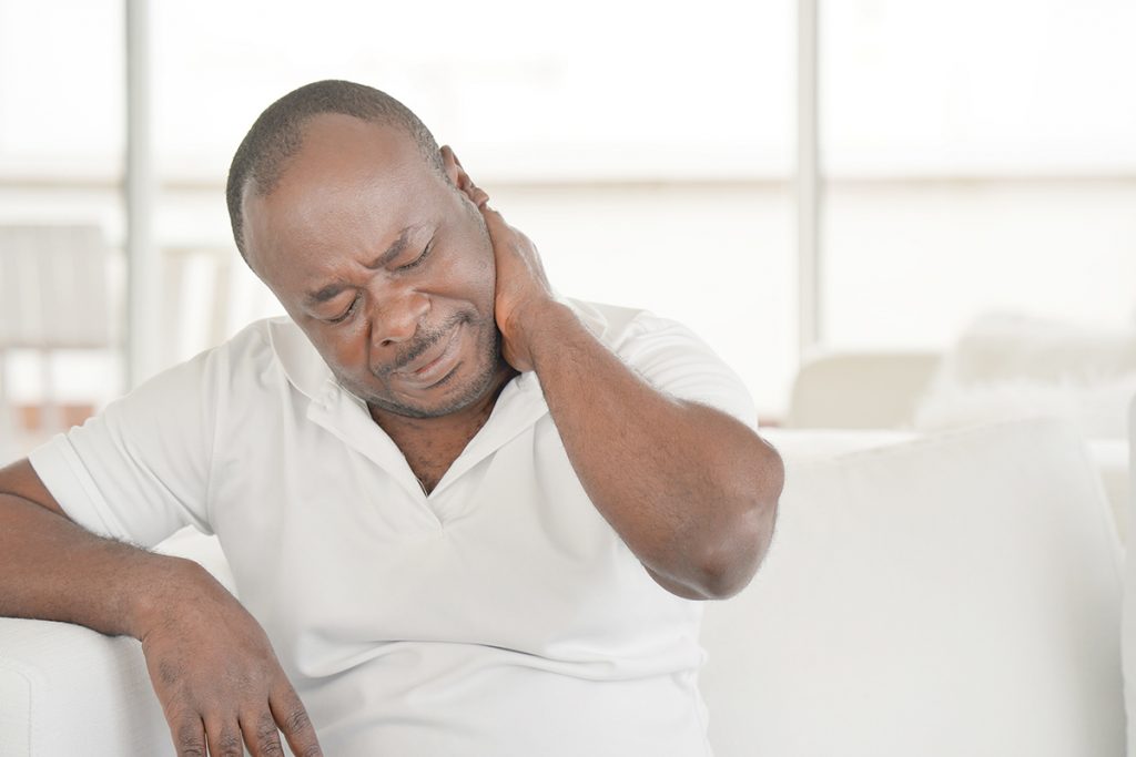 A gentleman rubs his neck due to chronic pain.