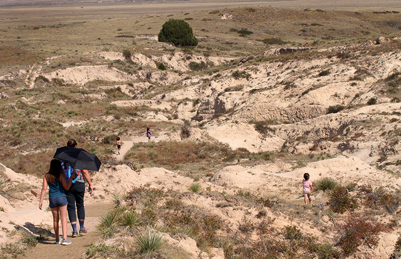 people walk down a trail into an arroyo at The Pawnee Buttes.