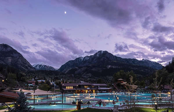 Ouray's hot springs pool at night with mountain peaks in the background.