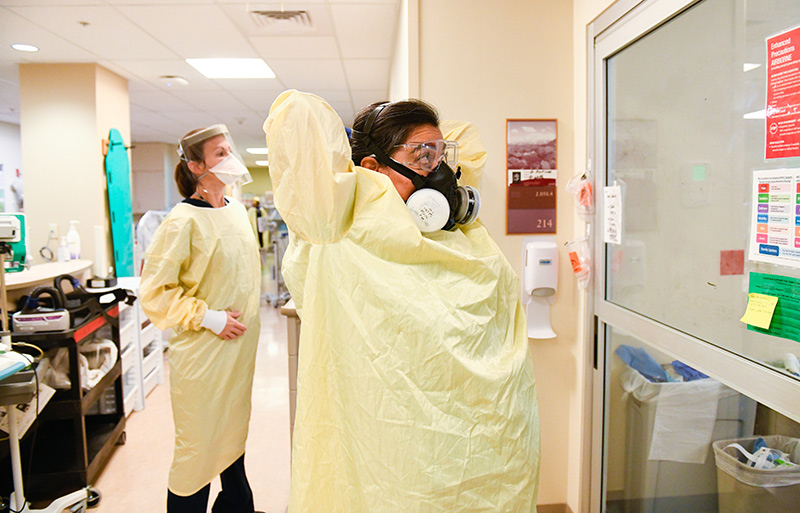 COVID-19 in Colorado. Nurse Olivia Thornton, left, and Dr. Abbey Lara, right suit up in protective gear as they prepare to tend to patients doubled up in an ICU room at UCHealth University of Colorado Hospital.