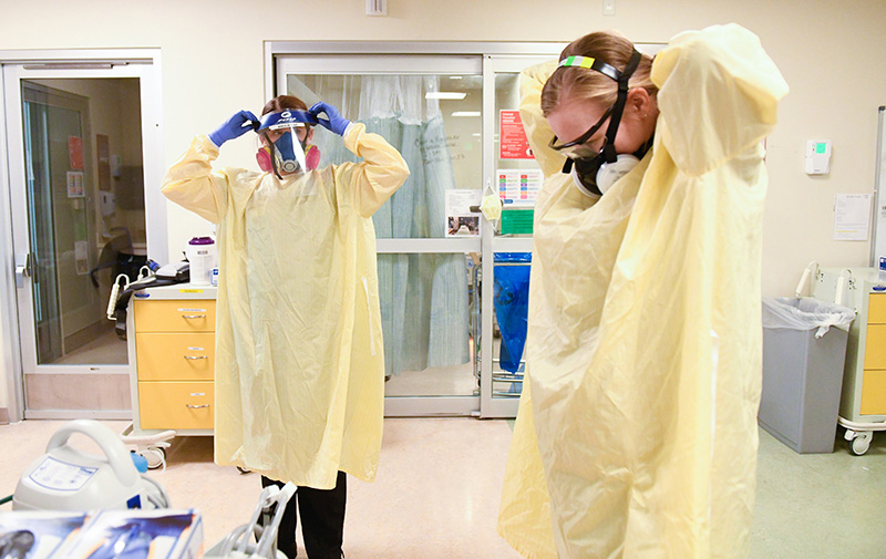 pandemic nurses, Kate McPhillips, left, and Caitlyn Greve, two COVID-19 ICU nurses suit up as they prepare to go into a room.