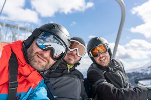 Colorado's first COVID-19 case likely stemmed from skiers who visited a Colorado resort town in December or January. Here, three me smile while riding a chairlift.