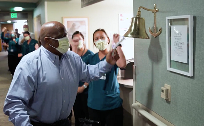 COVID-19 survivor Robert Carver rings a bell as he leaves the hospital.