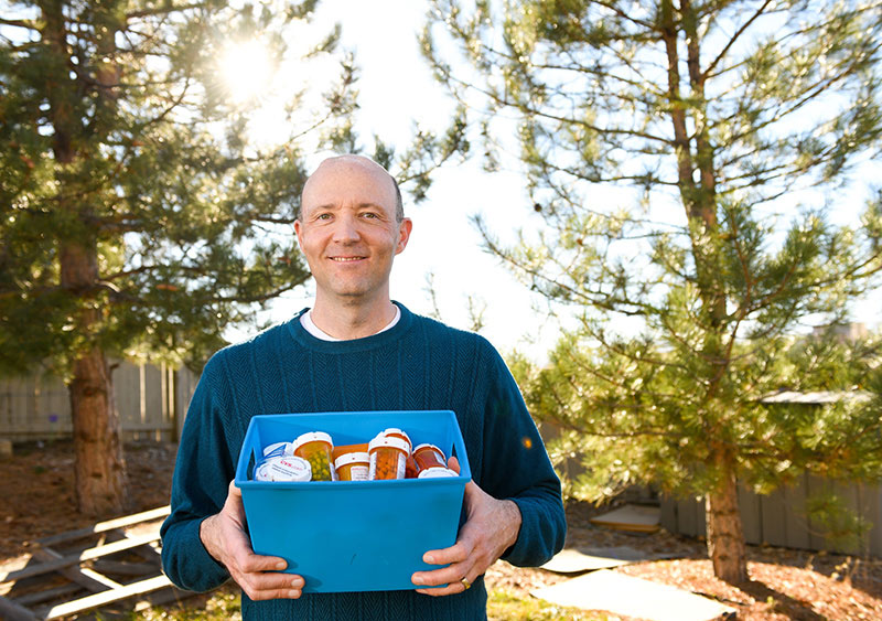 DBS for Parkinson's made it possible for Mike Whitt to stop taking medications. Here, he holds a container full of old medications.