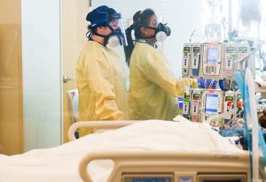 provider and nurse in the ICU at UCH using their COVID-19 care improvement knowledge to care for a patient.