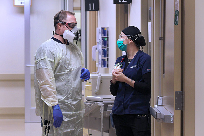 Front line workers at UCHealth Medical Center of the Rockies discuss a patient's care using their knowledge of COVID-19 care improvements.