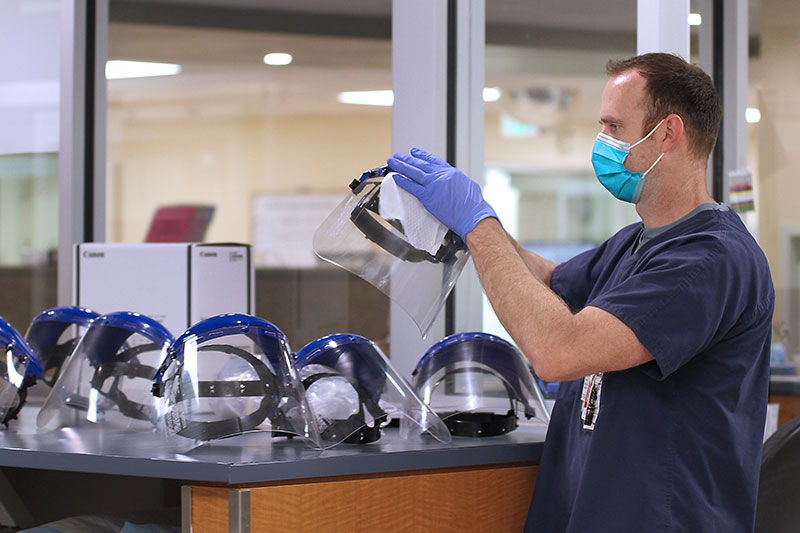 A nurse at UCHealth Medical Center of the Rockies sanitizes face shields.