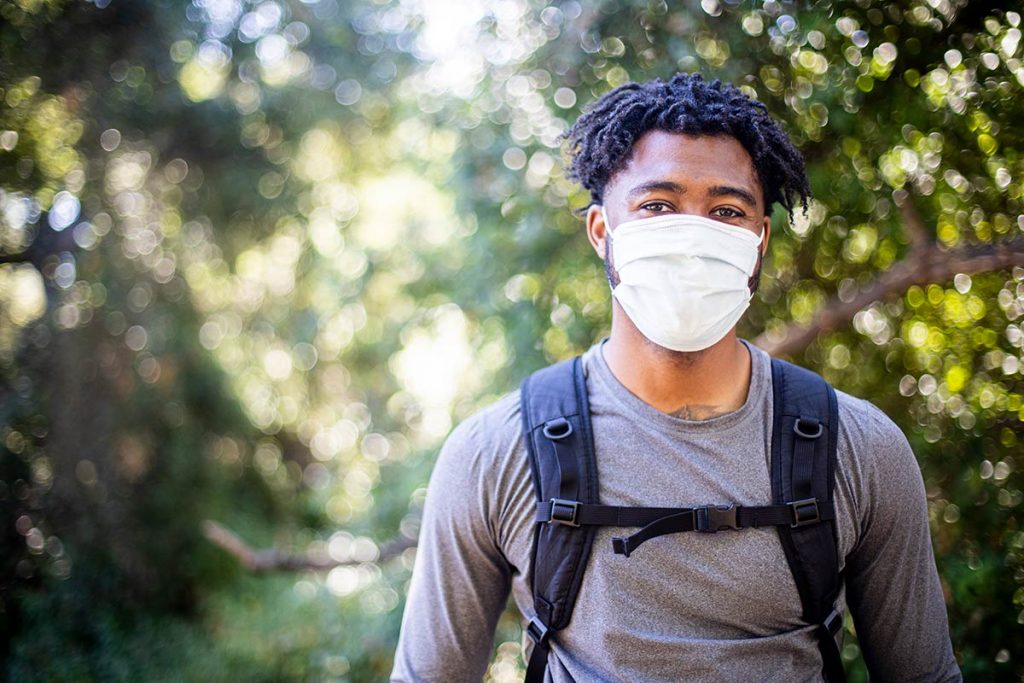 A man wearing a mask is out hiking.
