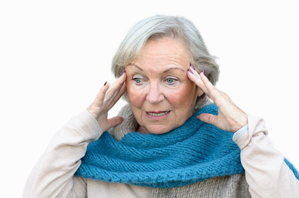 A woman with hands on her temples, trying to remember what she was doing and struggling from brain fog..