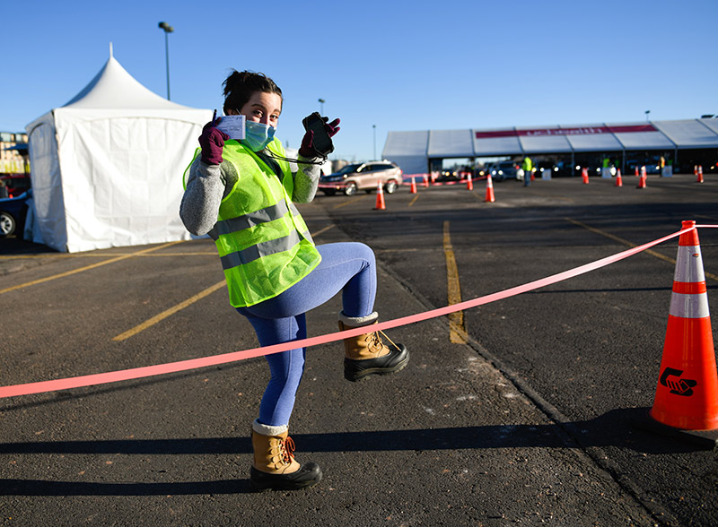 Allison Avery kicks up her legs as she holds vaccine cards during a mass vaccination clinic at Coors Field in Denver on Jan. 31. Avery is studying to become a physician assistant and volunteered to help at all future mass vaccination events.